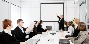 A CEO giving a presentation on a board, to his team and colleagues